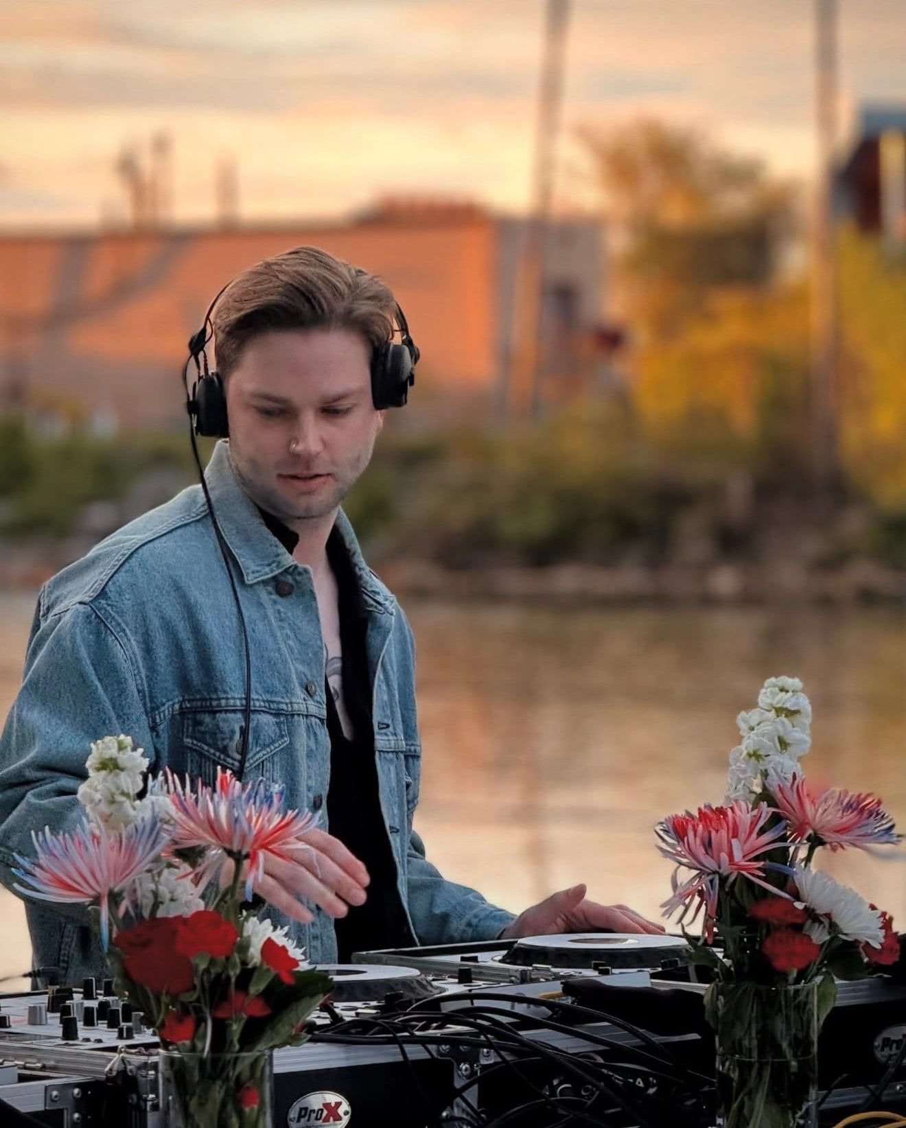 JohnLuc at the decks beside flowers, wearing headphones.